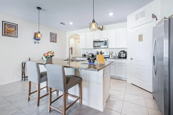 a kitchen with stainless steel appliances kitchen island granite countertop a table chairs and a refrigerator
