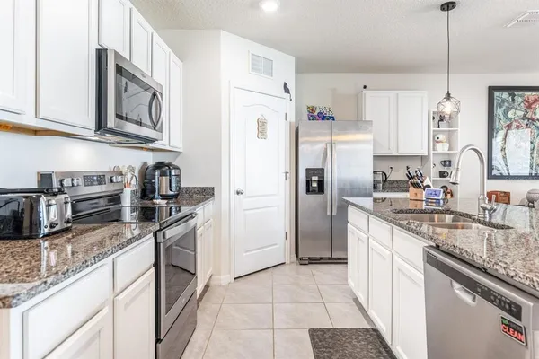 a kitchen with stainless steel appliances granite countertop a refrigerator a stove a sink a microwave and island