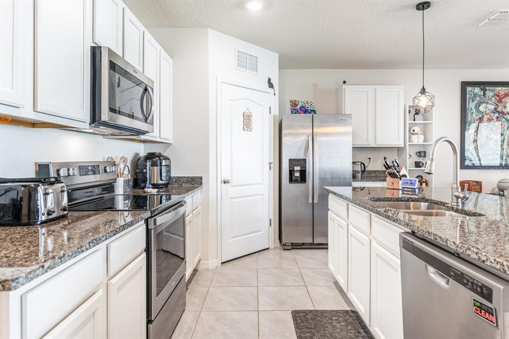 5381 Hickory Downs Way St. Cloud, FL 34771 - Photo 5 of 35 a kitchen with stainless steel appliances granite countertop a refrigerator a stove a sink a microwave and island