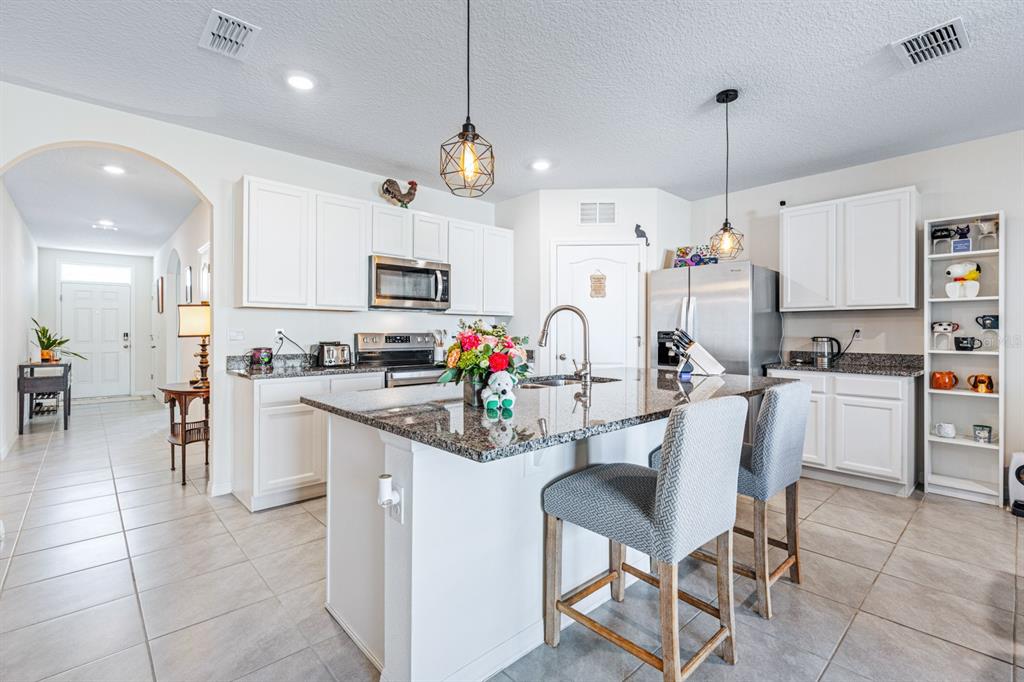 5381 Hickory Downs Way St. Cloud, FL 34771 - Photo 6 of 35 a kitchen with microwave a stove and chairs