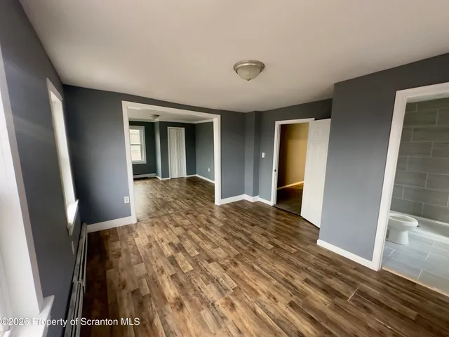 a large white kitchen with kitchen island a stove a sink dishwasher and a refrigerator with wooden floor