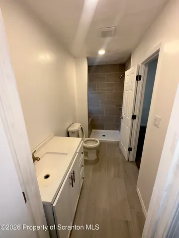 a view of an empty room with wooden floor and window