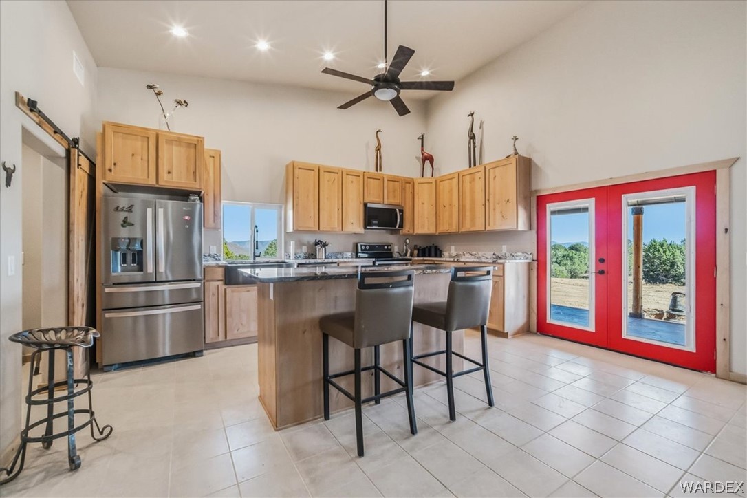 10374 East Happy Trails Road Kingman, AZ 86401 - Photo 14 of 68 a kitchen with stainless steel appliances kitchen island granite countertop a refrigerator a stove a microwave oven a dining table and chairs with the view