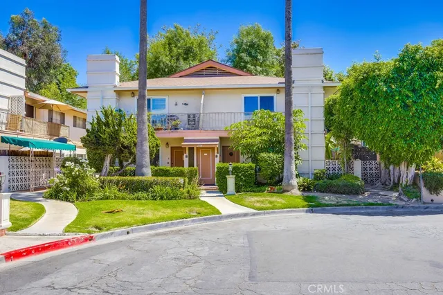 a view of yellow house with a yard and palm trees