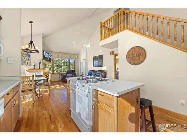 a kitchen with a cabinets a stove a sink dishwasher and a dining table with wooden floor