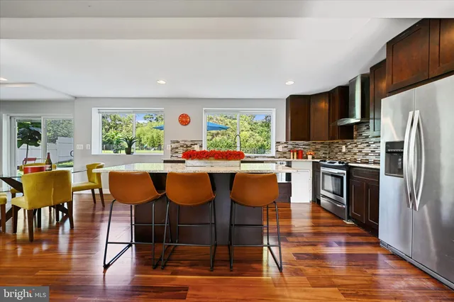 a kitchen with stainless steel appliances granite countertop a table chairs refrigerator and a dining table view