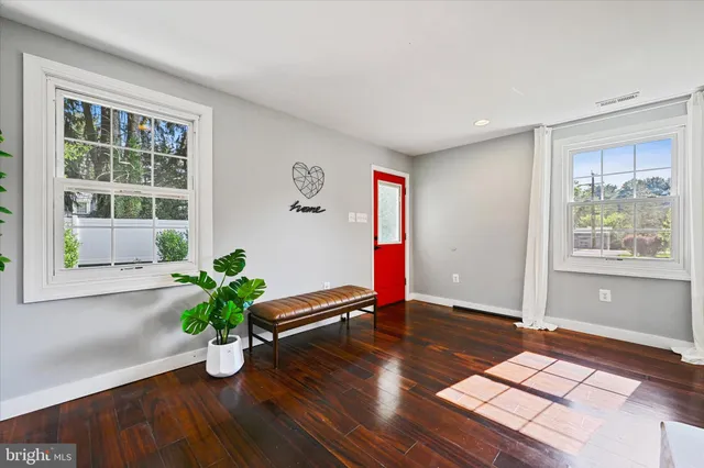 a view of an empty room with window and wooden floor