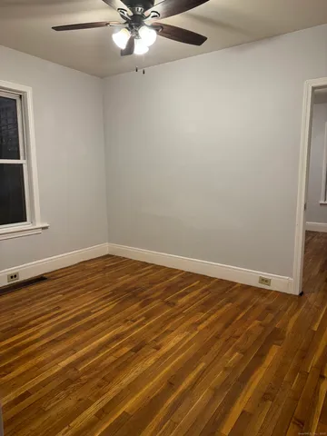an empty room with wooden floor and fan