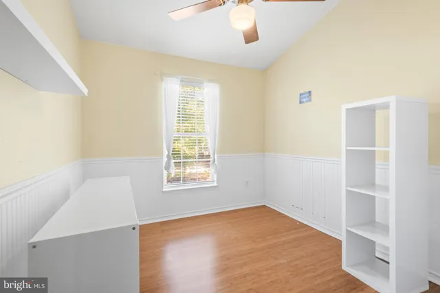 an empty room with a window and chandelier fan