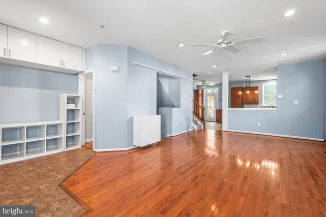 a view of an empty room with wooden floor and a kitchen