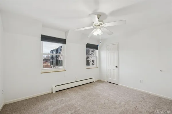 an empty room with windows and fan