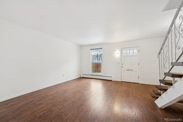 a view of an empty room with wooden floor and stairs