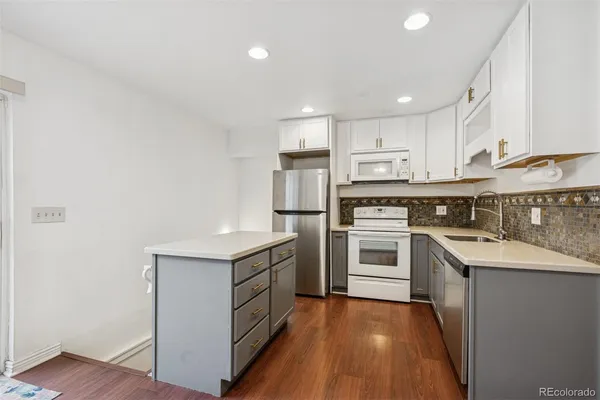 a kitchen with stainless steel appliances granite countertop a stove top oven a sink and a refrigerator