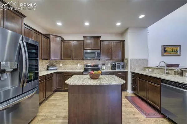 a kitchen with kitchen island granite countertop stainless steel appliances and sink