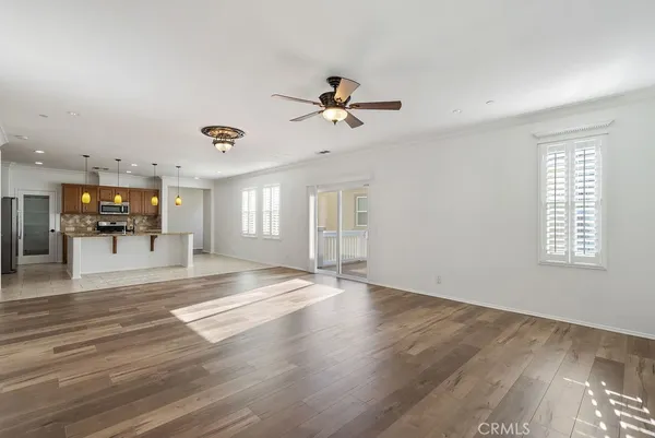 a view of an empty room with kitchen and window