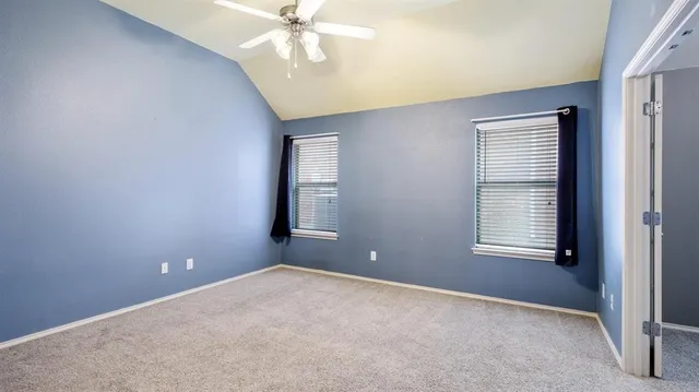 an empty room with windows and fan