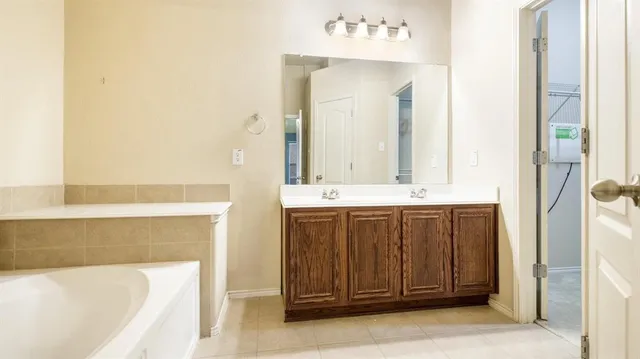 a bathroom with a double vanity sink mirror and a bathtub