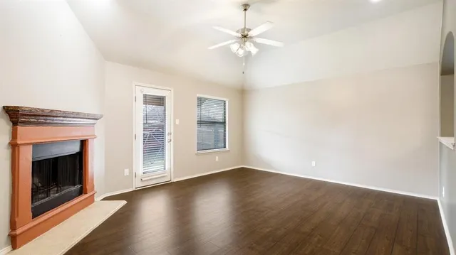 an empty room with wooden floor fireplace and windows
