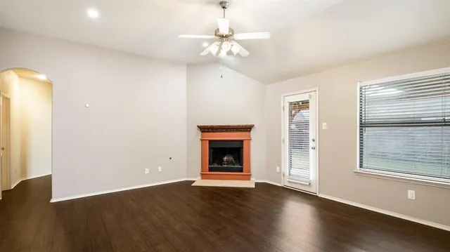 an empty room with wooden floor chandelier and windows