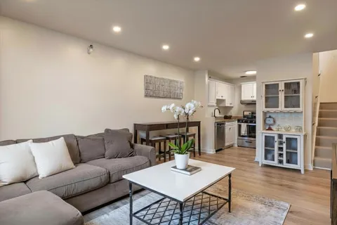 a living room with furniture kitchen view and a wooden floor