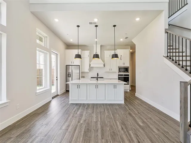 a large white kitchen with wooden floors stainless steel appliances