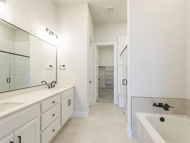 a spacious bathroom with a double vanity sink a mirror and a bathtub