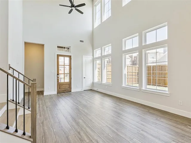 an empty room with wooden floor fan and windows