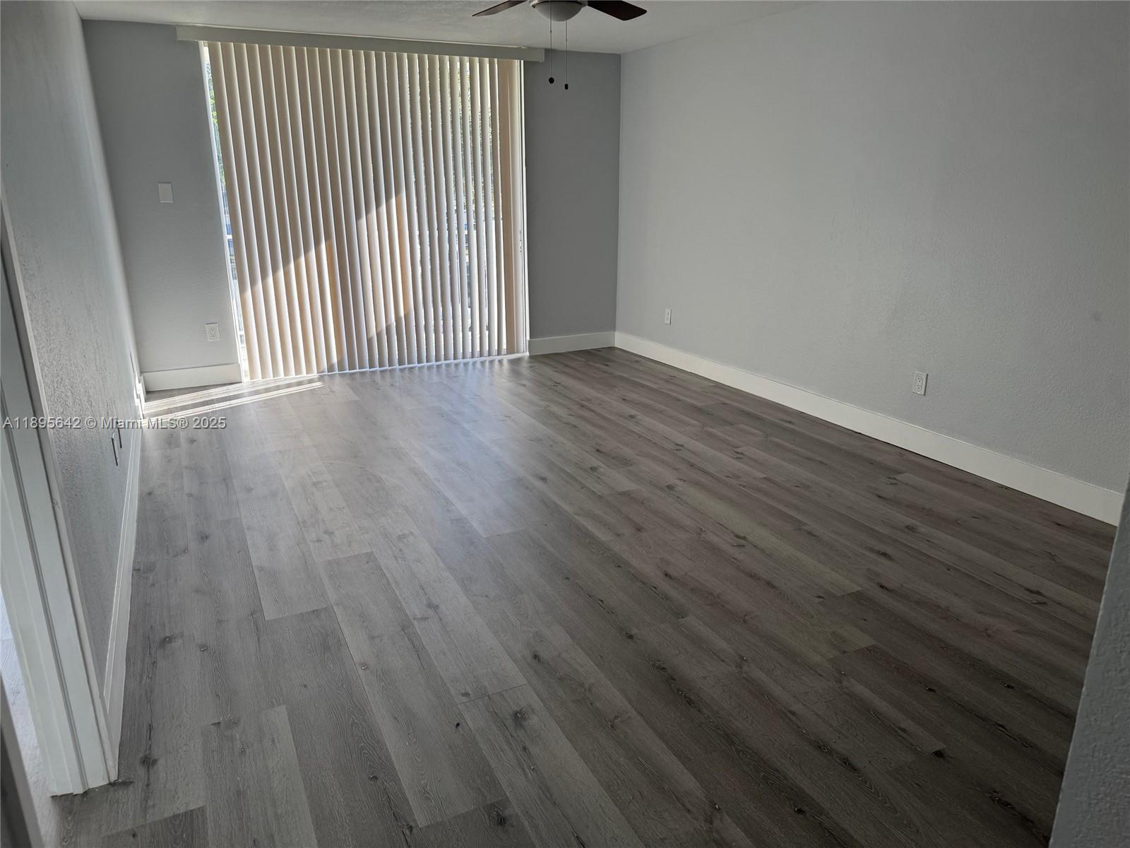 494 Northwest 165th Street, Unit C207 Miami, FL 33169 - Photo 7 of 14 an empty room with wooden floor and windows