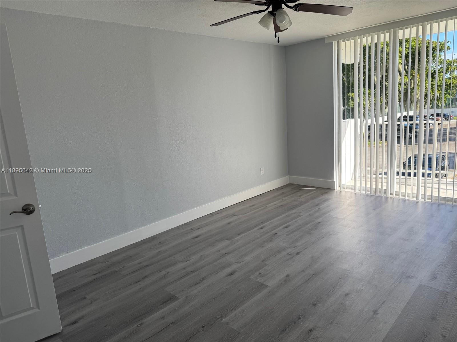 494 Northwest 165th Street, Unit C207 Miami, FL 33169 - Photo 9 of 14 a view of a livingroom with wooden floor and a ceiling fan