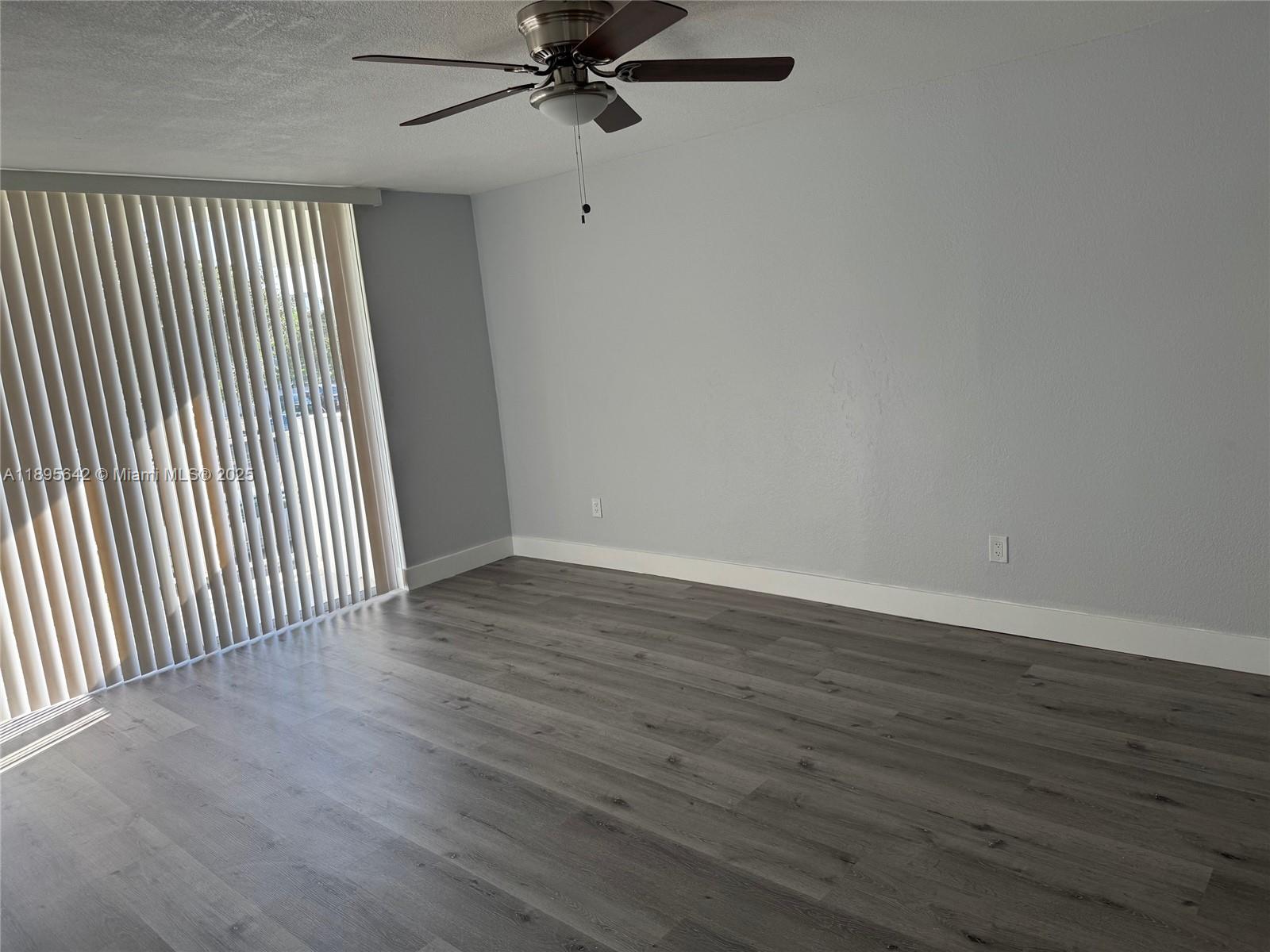 494 Northwest 165th Street, Unit C207 Miami, FL 33169 - Photo 10 of 14 an empty room with wooden floor fan and windows