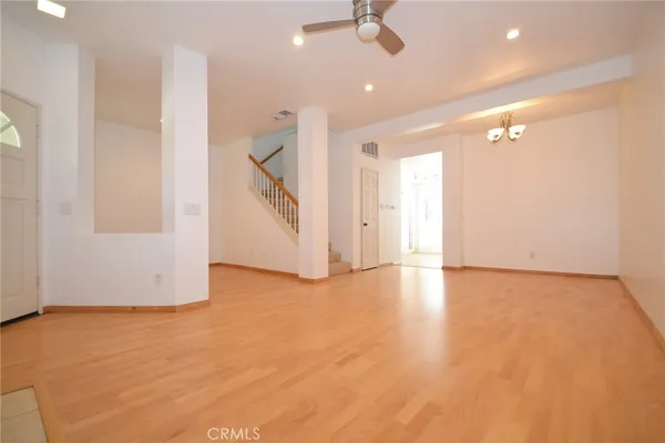 an empty room with wooden floor fan and windows