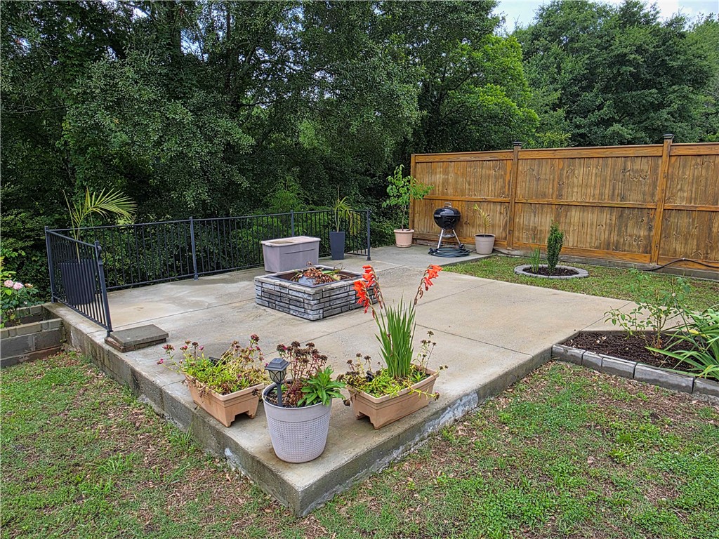 224 Bronson Ridge Anderson, SC 29621 - Photo 27 of 42 A well-appointed patio with a fire pit offers a secluded outdoor escape, framed by lush greenery.