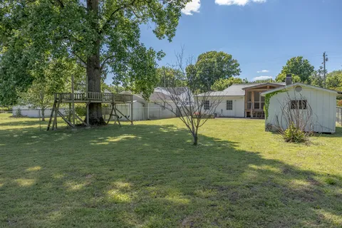 a view of a house with backyard and a tree