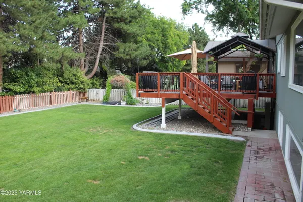 a view of wooden house with a deck and a yard