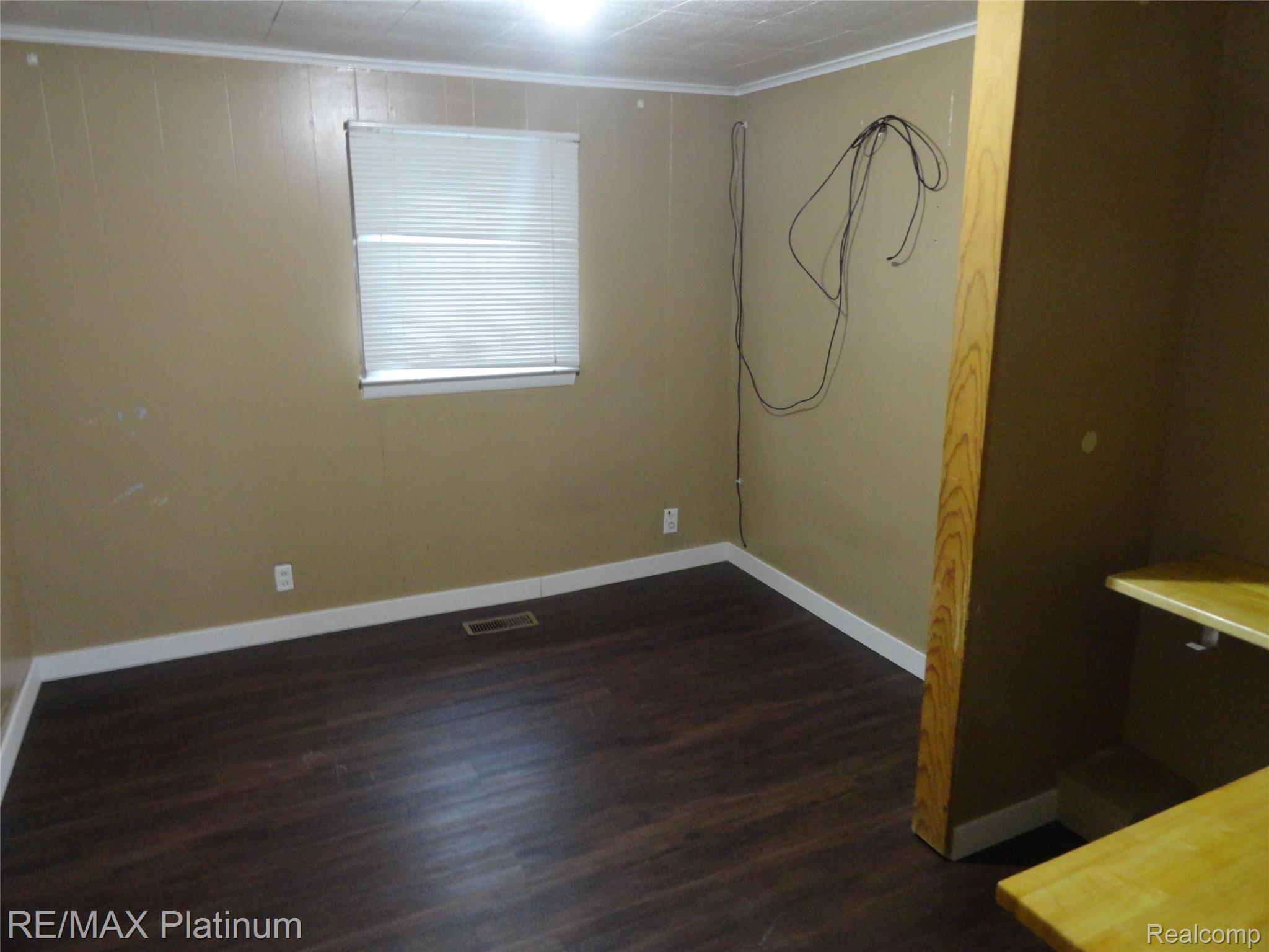 3396 East Baldwin Road Grand Blanc, MI 48439 - Photo 8 of 16 Spare room with crown molding and dark wood-style flooring
