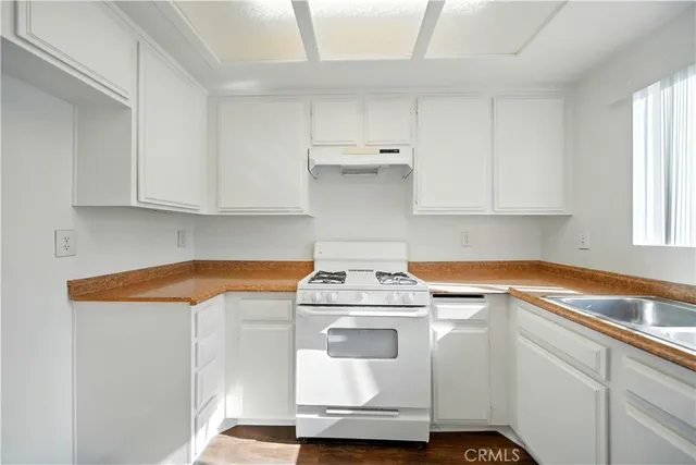 a utility room with stainless steel appliances white cabinets and a stove