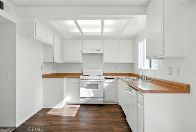 a kitchen with granite countertop a sink stove and cabinets