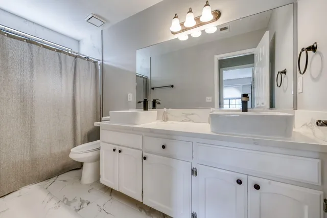 a bathroom with a double vanity sink mirror and toilet