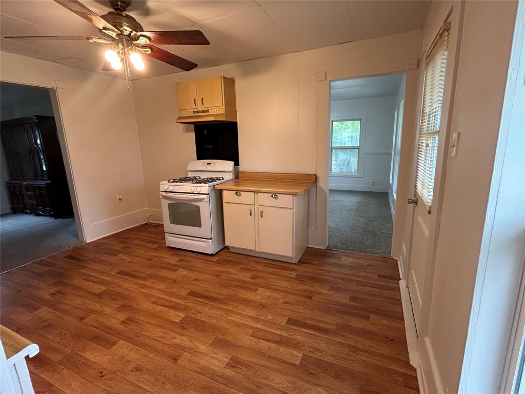 302 North Commerce Savoy, TX 75479 - Photo 17 of 32 a view of a kitchen with a sink a refrigerator a ceiling fan and wooden floor