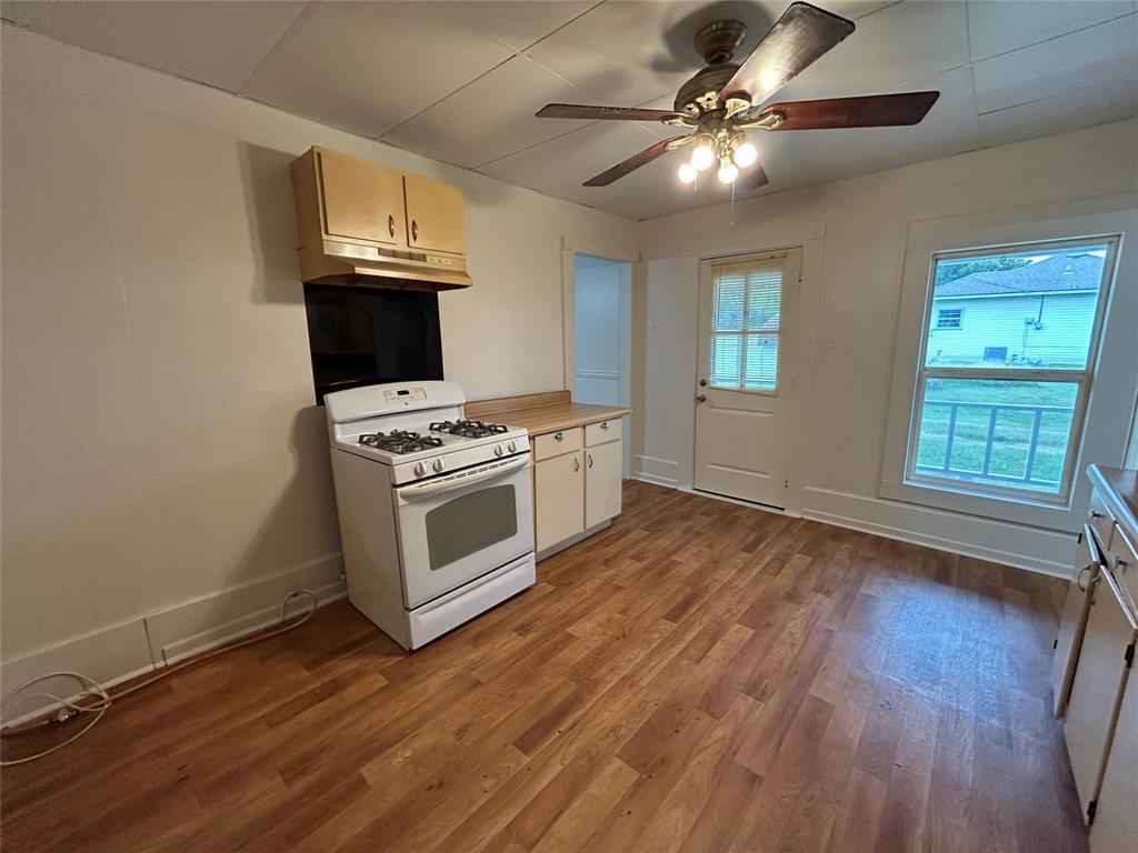 302 North Commerce Savoy, TX 75479 - Photo 23 of 32 a kitchen with granite countertop wooden floors and white stainless steel appliances