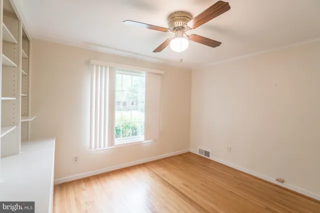 an empty room with wooden floor fan and windows