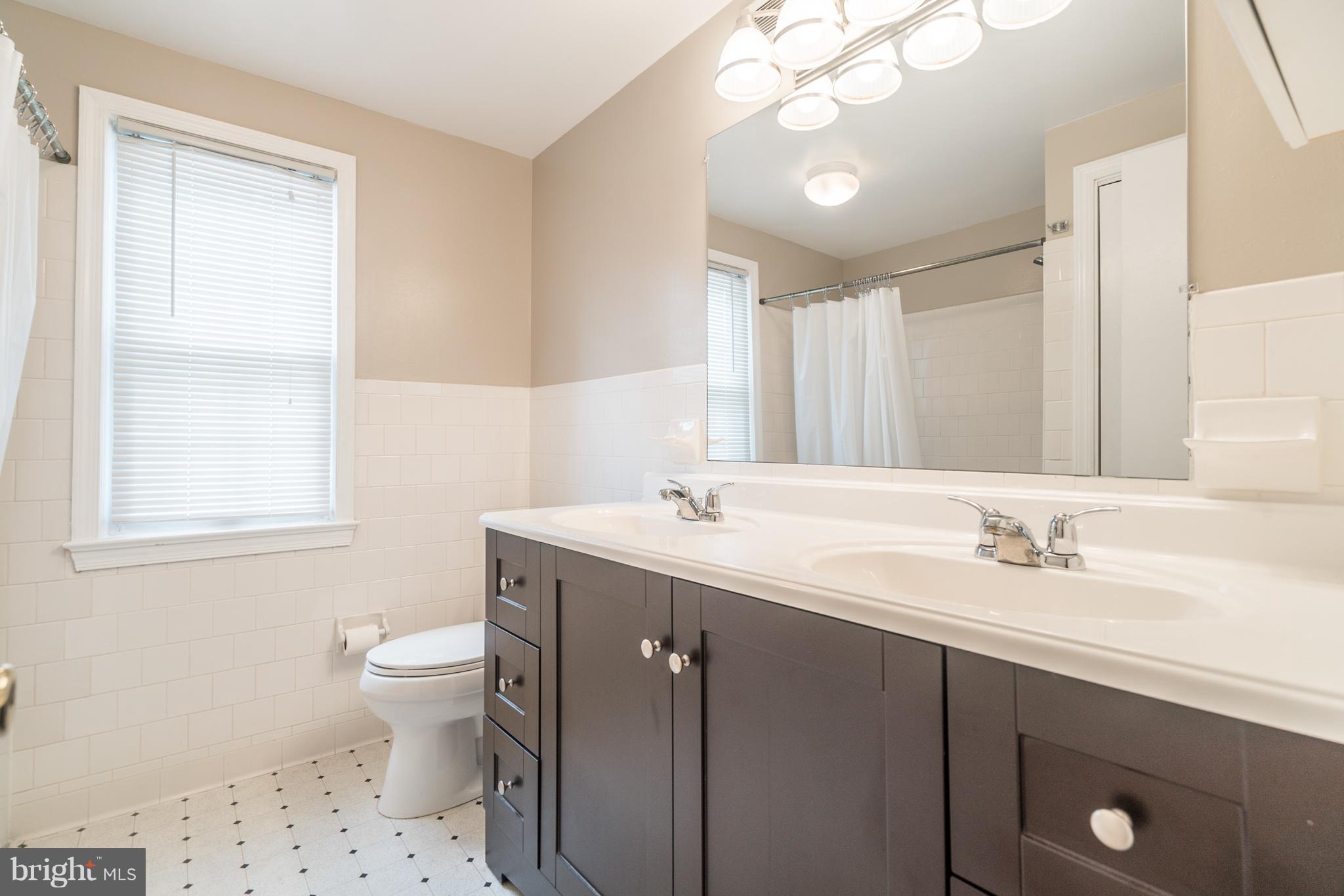 6104 28th Street North Arlington, VA 22207 - Photo 23 of 30 a bathroom with a double vanity sink a toilet and a mirror
