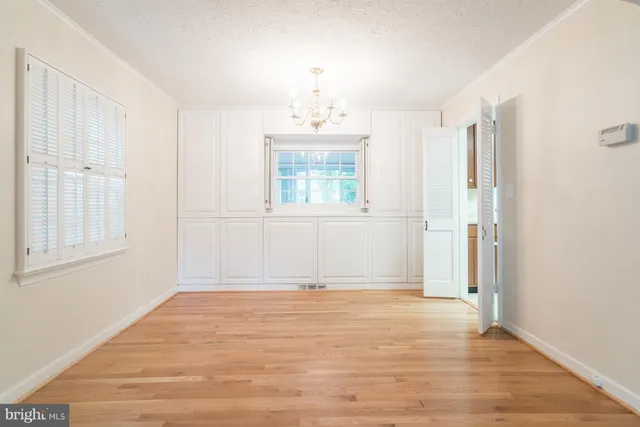 an empty room with wooden floor cabinet and windows