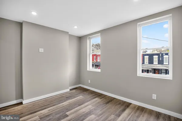 an empty room with wooden floor closet and windows