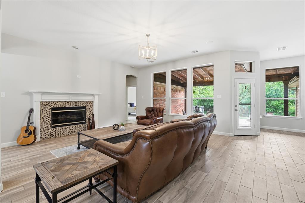2402 Ravinia Drive Corinth, TX 76208 - Photo 12 of 40 Spacious living area featuring light-colored tile flooring, a fireplace with a decorative tile surround, and large windows providing abundant natural light