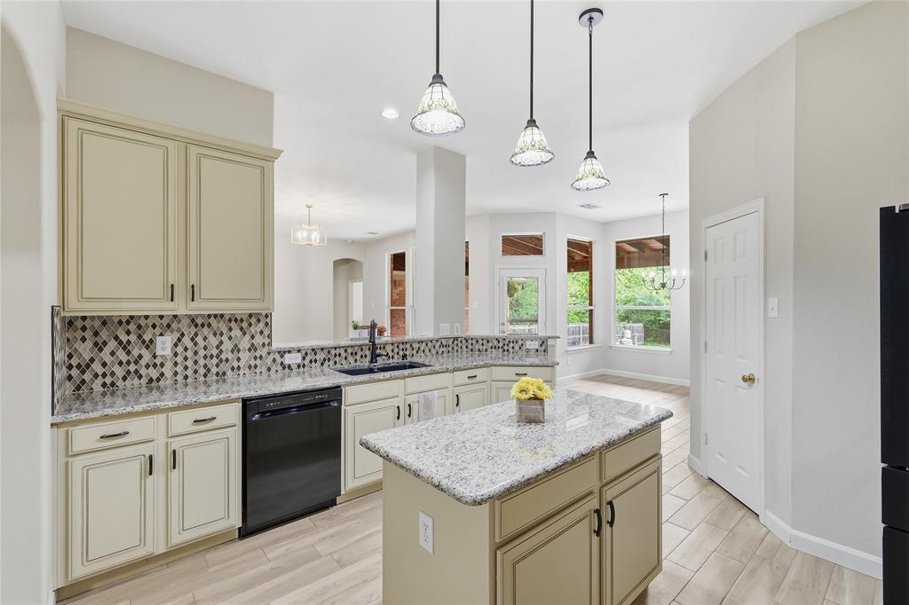 2402 Ravinia Drive Corinth, TX 76208 - Photo 18 of 40 The kitchen features light-colored cabinetry with dark hardware, a mosaic tile backsplash, and granite countertops