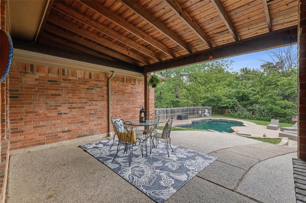2402 Ravinia Drive Corinth, TX 76208 - Photo 2 of 40 Covered patio featuring an exposed wood beam ceiling, brick wall, and view of the pool area