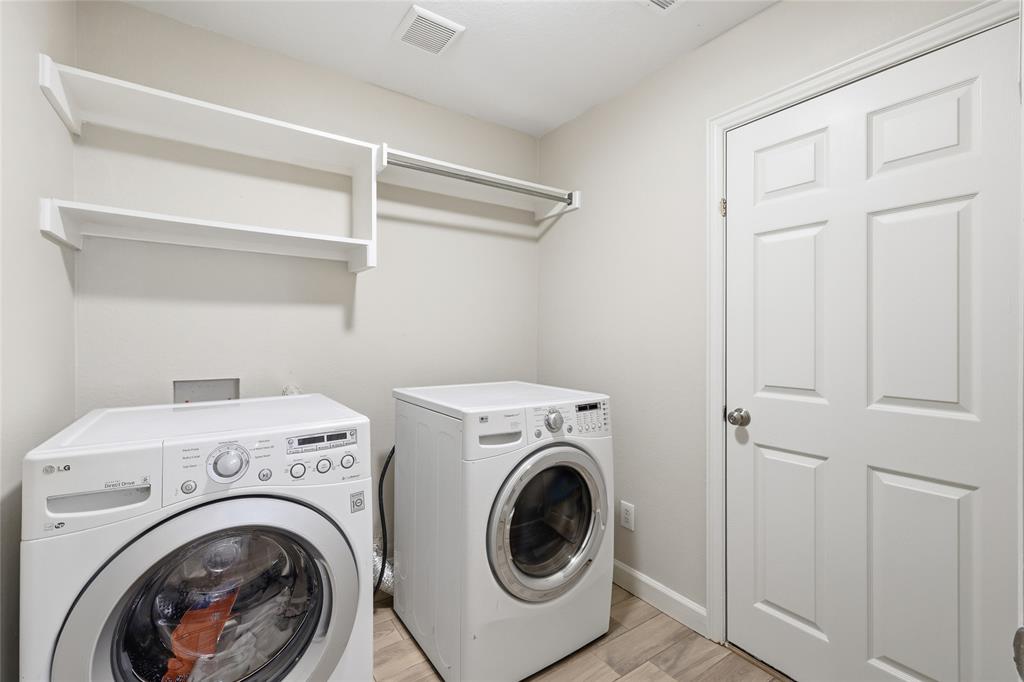 2402 Ravinia Drive Corinth, TX 76208 - Photo 22 of 40 Laundry area featuring a washer and dryer that will stay, white shelving, and a hanging rod