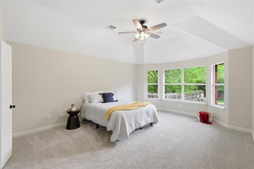 2402 Ravinia Drive Corinth, TX 76208 - Photo 23 of 40 This bedroom features light-colored carpeting, a vaulted ceiling with a ceiling fan, and a bay window area providing views of the swimming pool and back yard