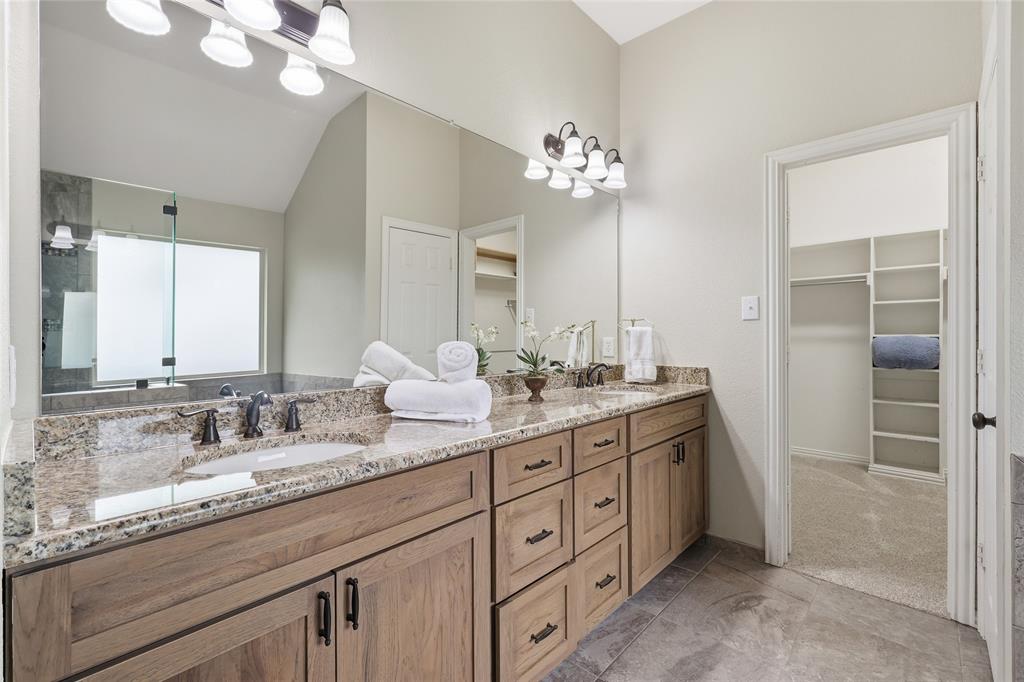 2402 Ravinia Drive Corinth, TX 76208 - Photo 26 of 40 Bathroom featuring a double vanity with granite countertops, undermount sinks, and wood cabinetry